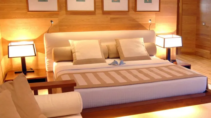 Adaaran Prestige Water Villas, Мальдивы — интерьер виллы Adaaran Prestige Water Villas — уютная спальня с деревянной отделкой и выходом на террасу