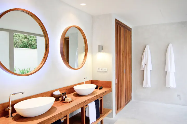 Amilla Maldives Resort and Residences — ванная комната с двумя раковинами и круглыми зеркалами