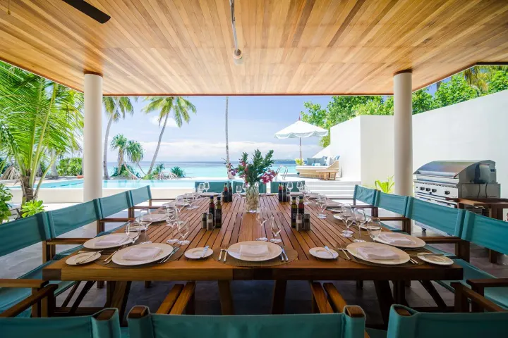 Amilla Maldives Resort and Residences — большой обеденный стол на террасе у бассейна
