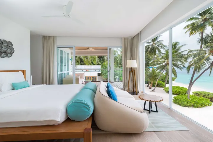 Amilla Maldives Resort and Residences — светлая спальня с большой кроватью и зоной отдыха