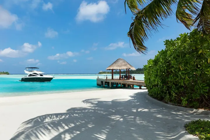Anantara Dhigu Maldives Resort, Мальдивы — прибытие Anantara Dhigu Maldives Resort — деревянный причал прибытия над сверкающей лагуной курорта