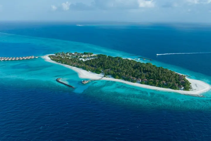 Avani+ Fares Maldives Resort — панорамный вид сверху на зелёный остров Фарес и коралловый риф