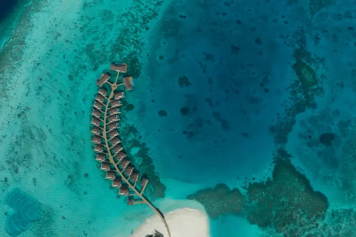 Avani+ Fares Maldives Resort — вид с высоты на бирюзовую бухту и цепочку водных вилл