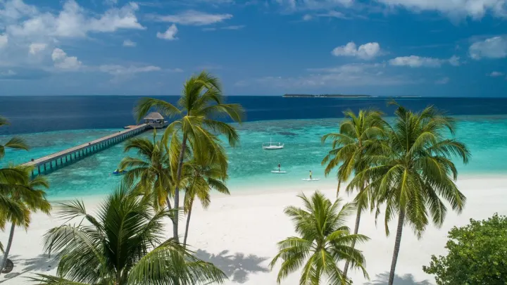 Baglioni Resort Maldives, Мальдивы — пляж Baglioni Resort Maldives — люди катаются на сапбордах вдоль пляжа и пирса