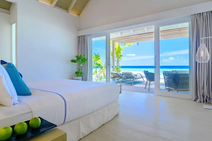 Baglioni Resort Maldives, Мальдивы — интерьер виллы Baglioni Resort Maldives — светлая спальня с двуспальной кроватью и видом на пляж