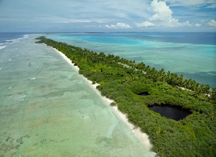 Canareef Resort Maldives — панорамный вид сверху на протяжённый зелёный остров и лагуну