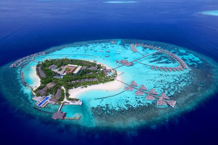 Centara Grand Island Resort & Spa Maldives — вид сверху на зеленый остров окруженный кольцом водных вилл