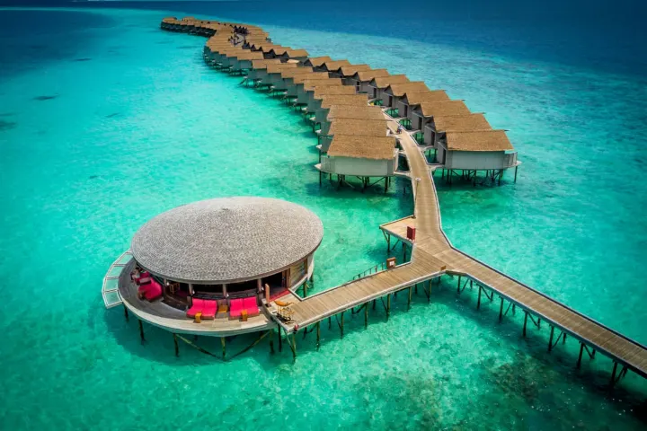 Centara Ras Fushi Resort & Spa Maldives — круглый ресторан на воде и длинная ветка водных вилл