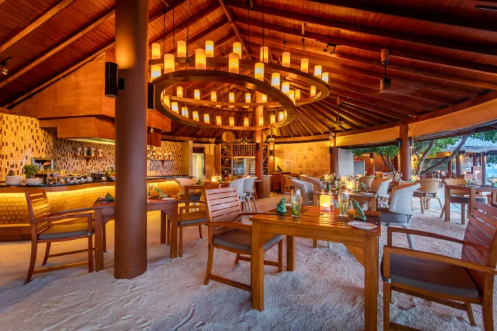 Centara Ras Fushi Resort & Spa Maldives, Мальдивы — ресторан Centara Ras Fushi Resort & Spa Maldives — уютный ресторан с деревянной мебелью и песчаным полом