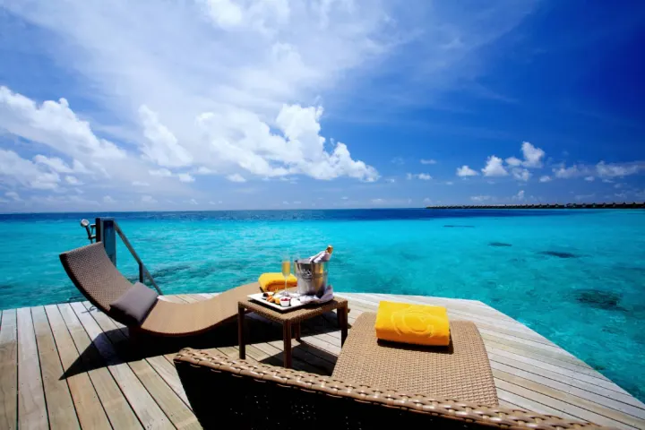 Centara Ras Fushi Resort & Spa Maldives, Мальдивы — вилла на воде Centara Ras Fushi Resort & Spa Maldives — шезлонги на открытой террасе водной виллы со спуском в воду