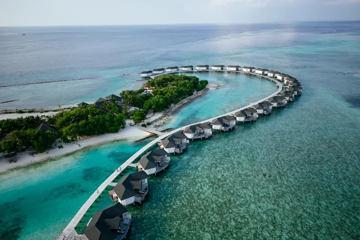 Cinnamon Dhonveli Maldives — аэросъёмка зеленого острова и изгиба водных вилл