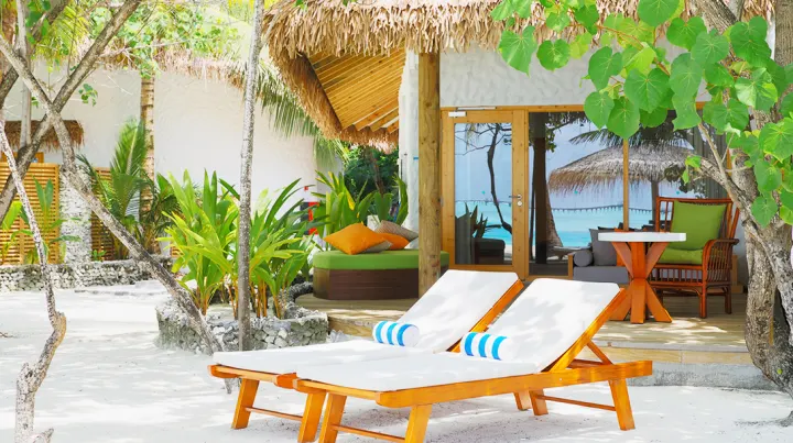 Cinnamon Dhonveli Maldives — терраса пляжной виллы с шезлонгами в тени деревьев