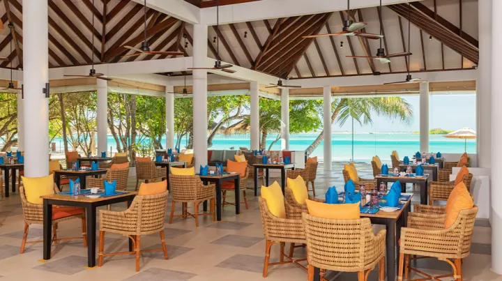 Cinnamon Dhonveli Maldives — открытая терраса ресторана с желтыми и фиолетовыми креслами