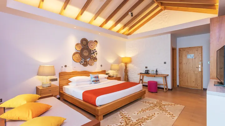 Cinnamon Dhonveli Maldives — спальня с деревянным полом и большой кроватью