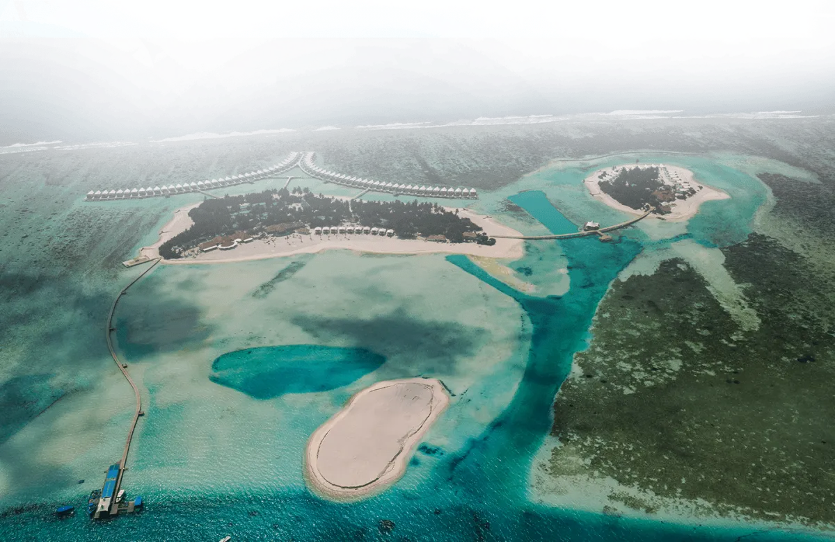 Cinnamon Hakuraa Huraa Maldives — вид сверху на узкий зеленый остров и окружающие рифы