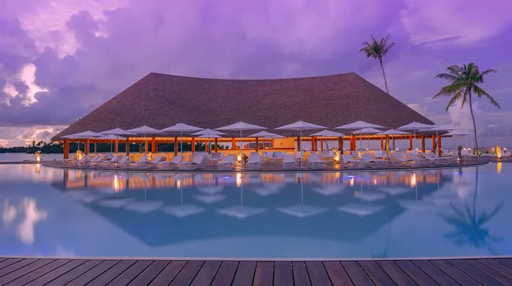 Cinnamon Velifushi Maldives, Мальдивы — бассейн Cinnamon Velifushi Maldives — главный бассейн и большое здание ресторана в вечерней подсветке