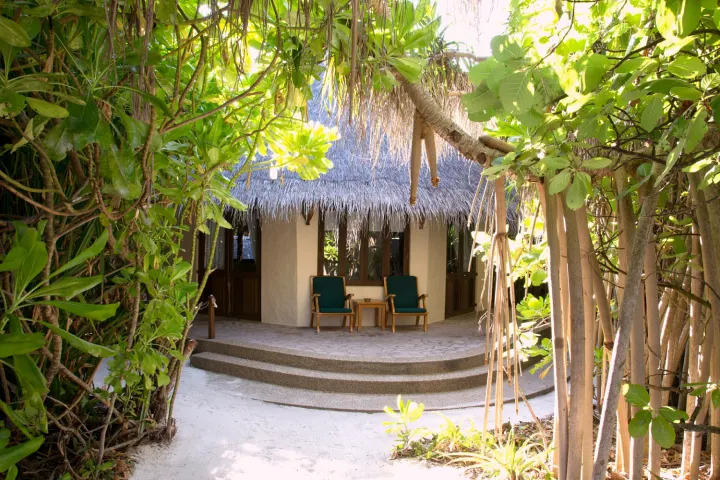 Coco Palm Dhuni Kolhu — спальня береговой виллы с высоким купольным потолком и кроватью под балдахином