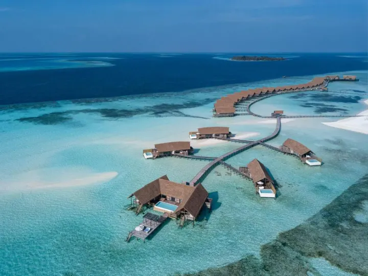 Cocoa Island by COMO — ночной бассейн водной виллы с подсветкой и закатом