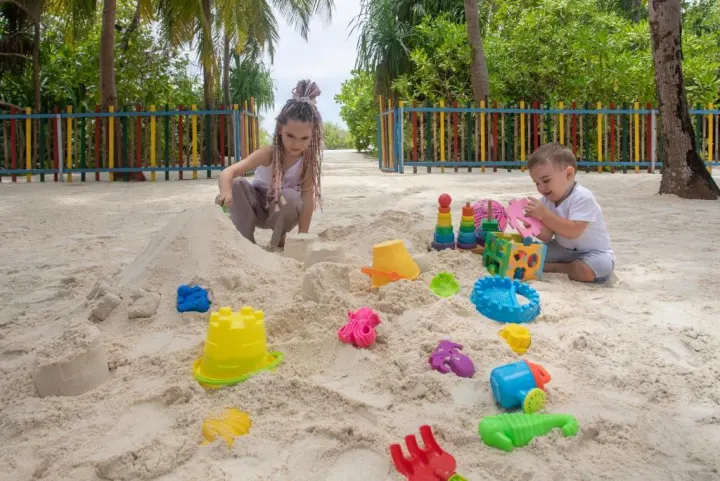 Cocoon Maldives — дети строят замки из песка на пляже