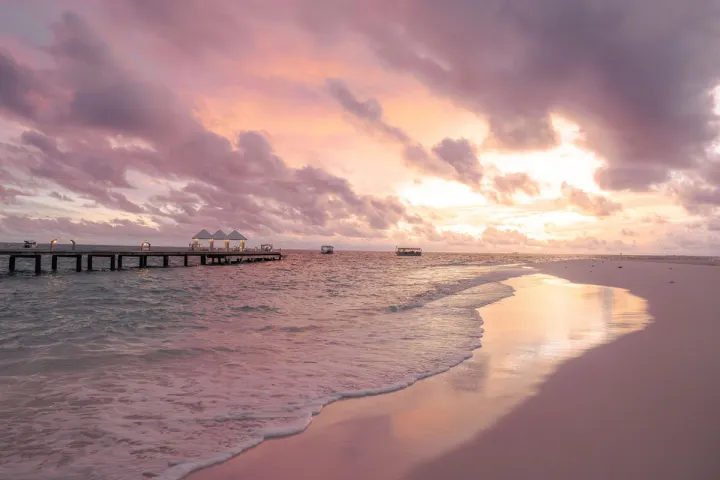 Diamonds Thudufushi Maldives, Мальдивы — пляж Diamonds Thudufushi Maldives — вечерний вид на деревянный пирс и водные виллы в лучах заката