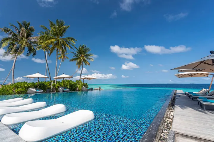 Fushifaru Maldives — инфинити-бассейн с белыми шезлонгами