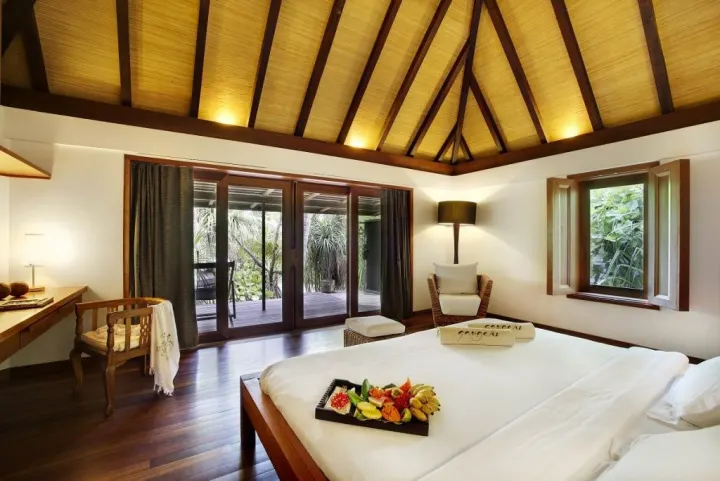 Gangehi Island Resort & Spa — интерьер спальни водной виллы с отделкой из натурального дерева