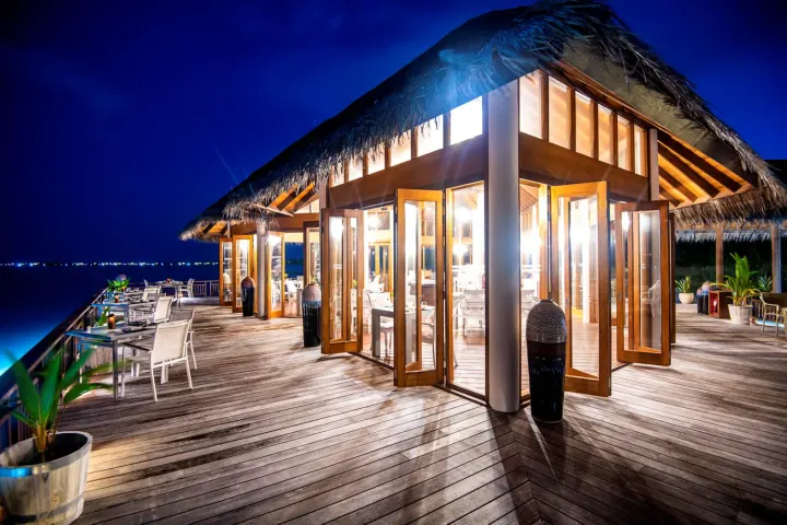 Hideaway Beach Resort & Spa, Мальдивы — ресторан Hideaway Beach Resort & Spa — терраса азиатского ресторана на сваях над вечерней лагуной