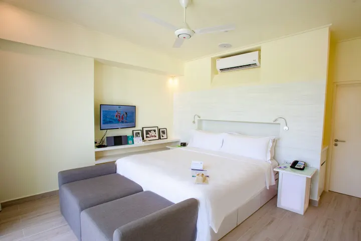 Holiday Inn Resort Kandooma Maldives — светлая спальня виллы с панорамными окнами в пол и видом на лагуну