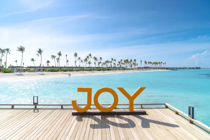 Joy Island Maldives, Мальдивы — пляж Joy Island Maldives — буквы JOY на деревянном пирсе у лагуны