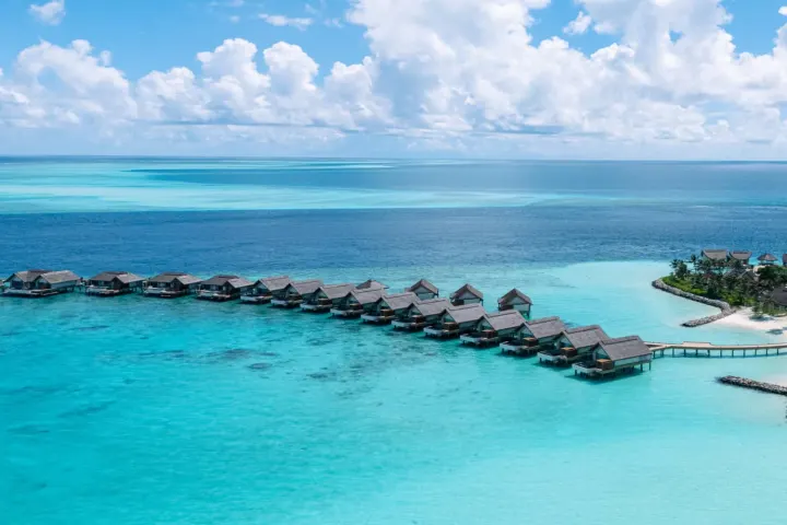 JW Marriott Kaafu Atoll Island Resort — панорамный вид с воздуха на остров и изящную дугу водных вилл