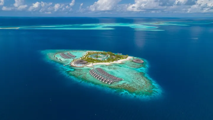 Kagi Maldives Spa Island — панорамный вид с воздуха на камерный остров и кольцо водных вилл