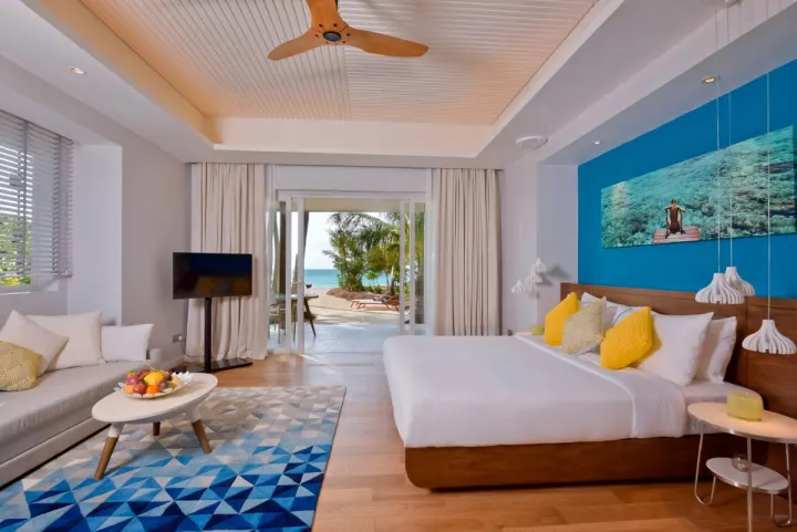 Kandima Maldives — спальня с ярким декором и выходом к пляжу