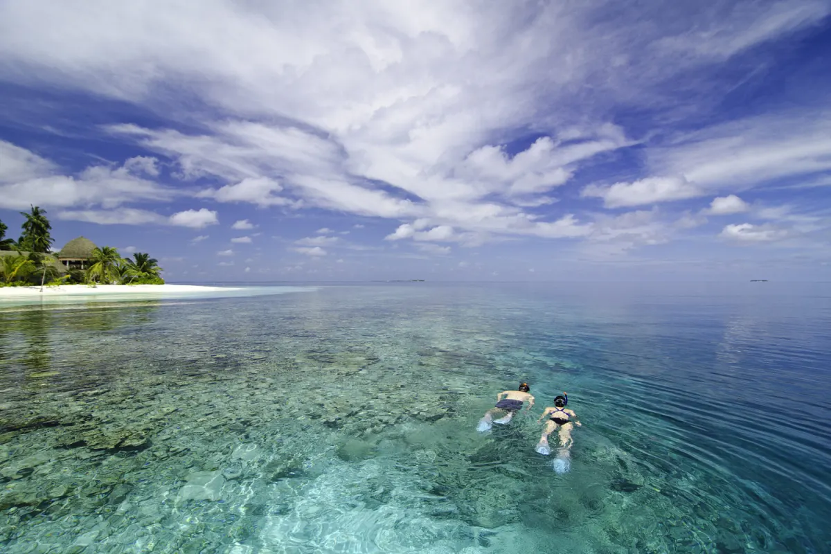 Kandolhu Maldives — двое гостей плавают с масками в прозрачном океане