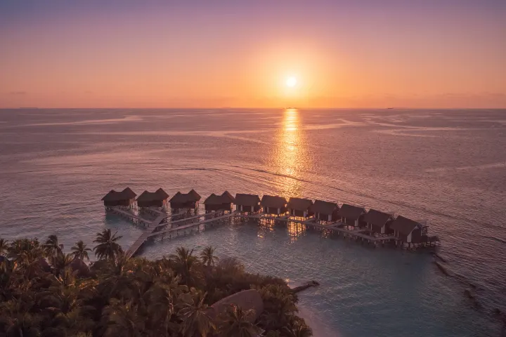 Kandolhu Maldives — водные виллы на фоне заката с высоты