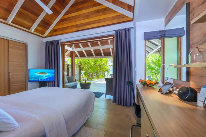 Kandolhu Maldives — светлая спальня пляжной виллы с рабочим местом