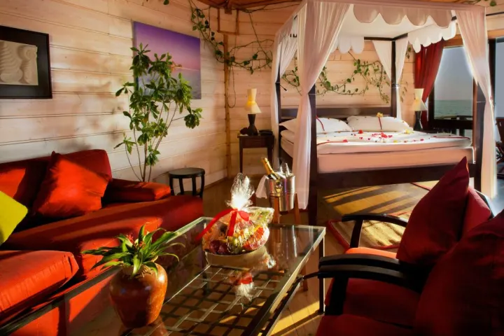 Kuredu Island Resort & Spa, Мальдивы — интерьер виллы Kuredu Island Resort & Spa — просторная спальня водной виллы с кроватью и диваном
