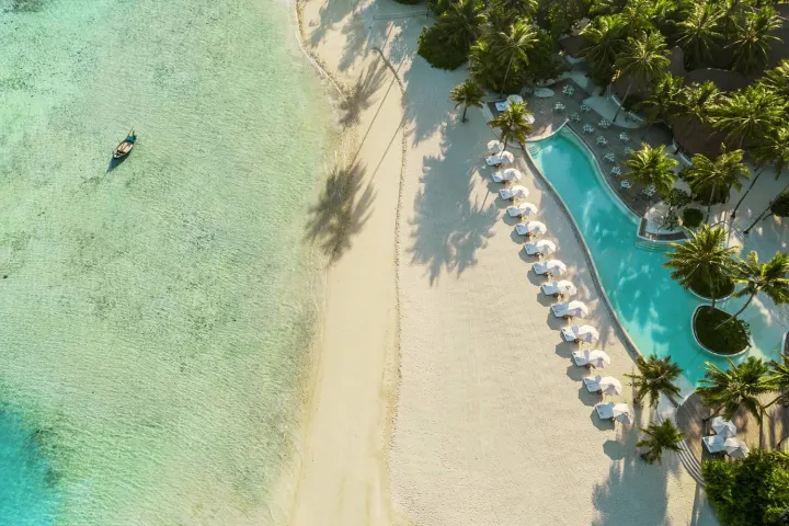 Maalifushi by COMO — белый пляж и бассейн вдоль берега с высоты