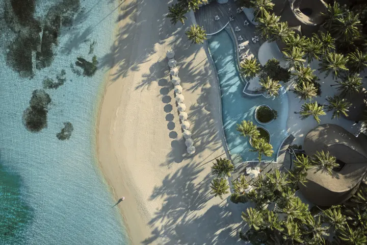 Maalifushi by COMO — вид сверху на бассейн у пляжа и пальмы