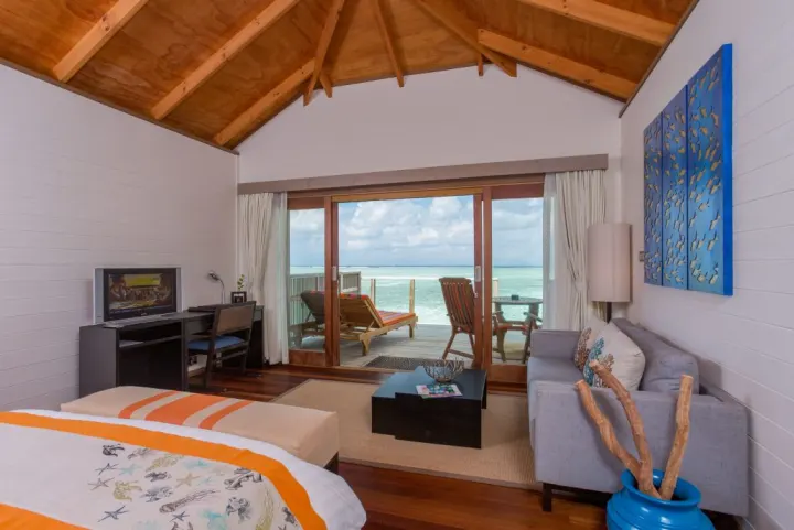 Meeru Island Resort & Spa — интерьер спальни с диваном и выходом на террасу