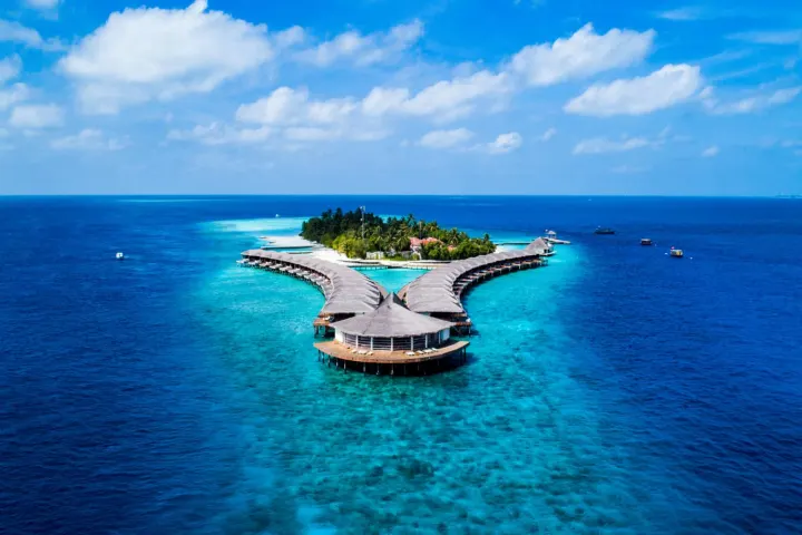 NAKAI Dhiggiri Resort — вид с высоты на бирюзовую лагуну и полукруглую линию водных вилл