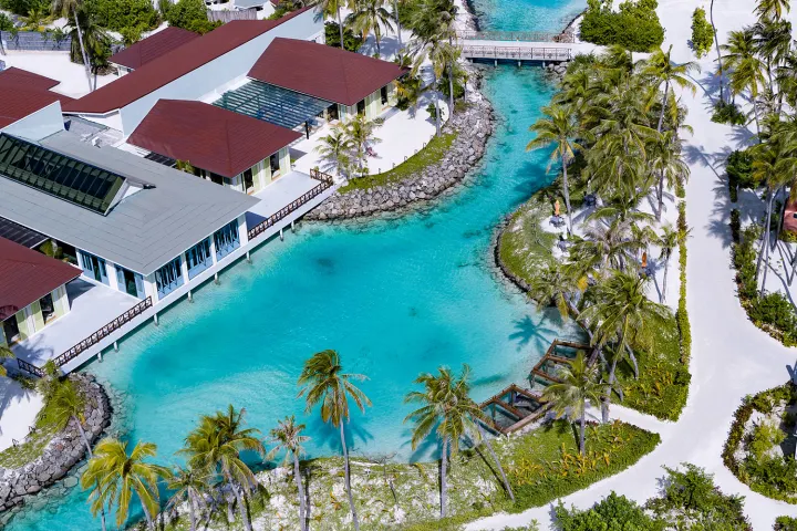 Oblu Xperience Ailafushi — вид на зеленую лагуну и постройки отеля