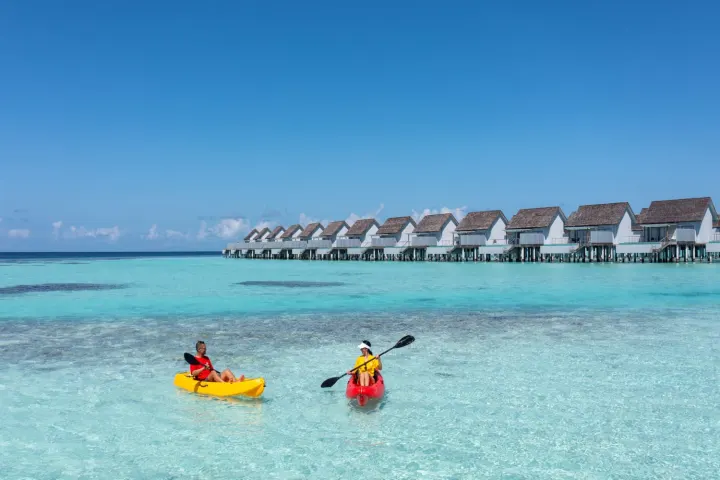 Outrigger Maldives Maafushivaru Resort — гости катаются на каяках по прозрачной воде