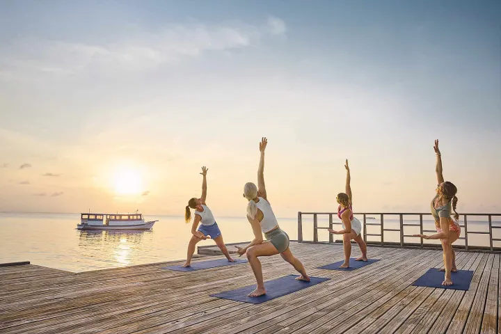 Robinson Club Maldives — занятия йогой на деревянной террасе на закате