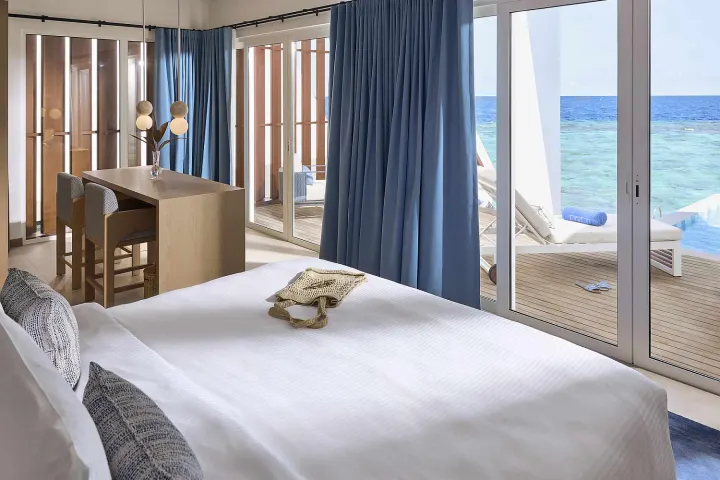 Robinson Club Maldives — светлая спальня с панорамным видом на лагуну