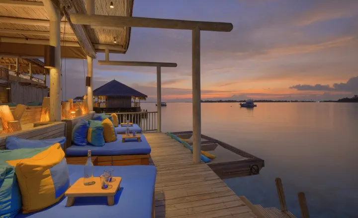 Six Senses Laamu, Мальдивы — бар Six Senses Laamu — лаунж с мягкими подушками и сеткой над водой на закате