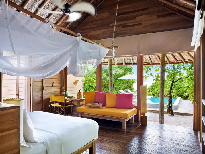 Six Senses Laamu, Мальдивы — интерьер виллы Six Senses Laamu — светлая спальня с кроватью под балдахином и зоной отдыха
