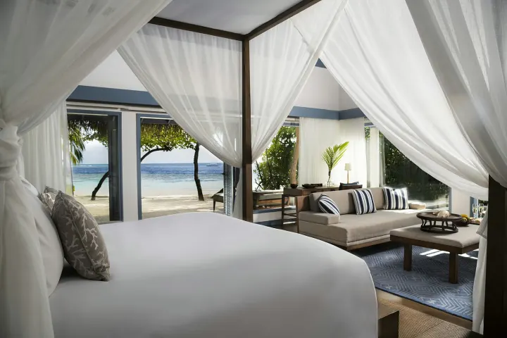 The Halcyon Private Isles Maldives (ex. Raffles Meradhoo), Мальдивы — интерьер виллы The Halcyon Private Isles Maldives (ex. Raffles Meradhoo) — элегантная спальня пляжной виллы с кроватью под балдахином и видом на сад