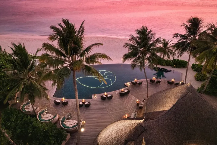The Nautilus Maldives — лаунж-бар у бассейна с мягкими шезлонгами на закате
