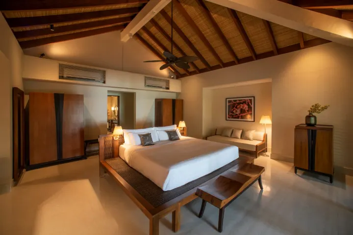 The Residence Maldives at Dhigurah — элегантная спальня пляжной виллы с высокими потолками и террасой