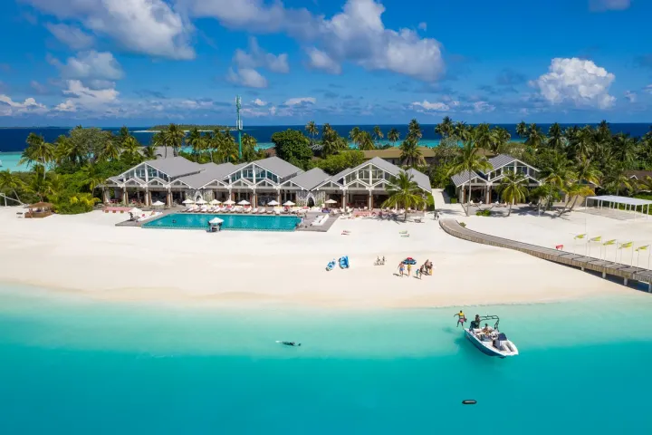 The Standard, Huruvalhi Maldives — вид с воздуха на полукруглую цепочку водных вилл в бирюзовой лагуне
